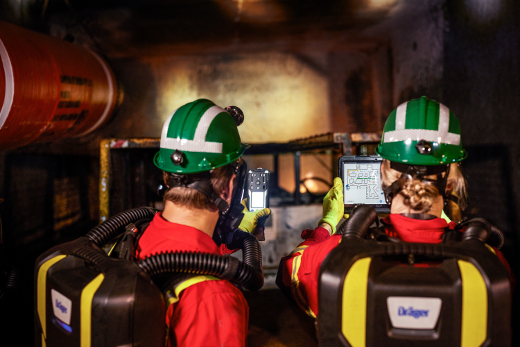 A group of miners wearing headlamps are standing in an underground passage.