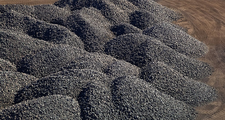 Piles of manganese ore are resting on the ground.