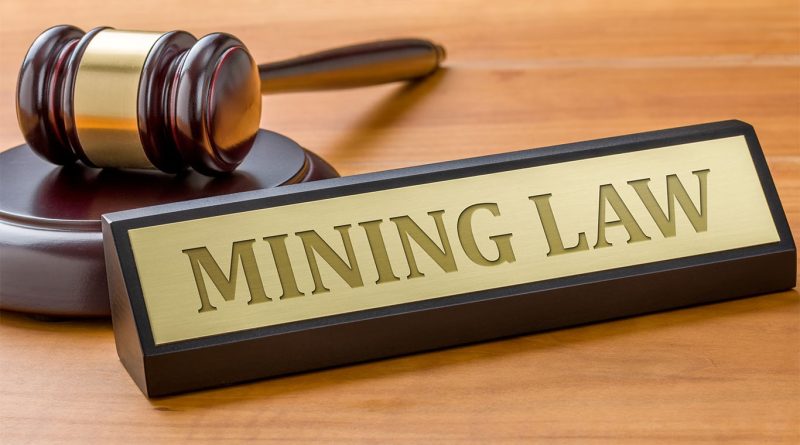 Court-room style image with a plaque on a desk saying 'mining law' to support U.S mining law article