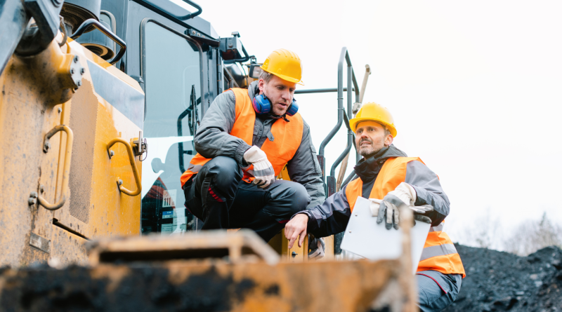 Two mining engineers in safety gear discussing operations at a mining site, highlighting the role of renewable energy in mining