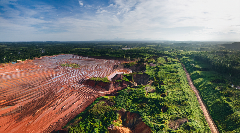 Aerial view of a reclaimed open pit mining site showing restored green vegetation alongside active earthworks, illustrating environmental reclamation in US mining.