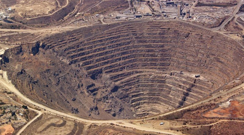 An open-pit mine overlooking a modern mineral processing facility and transport corridor, representing Africa's opportunity to build integrated critical mineral value chains.