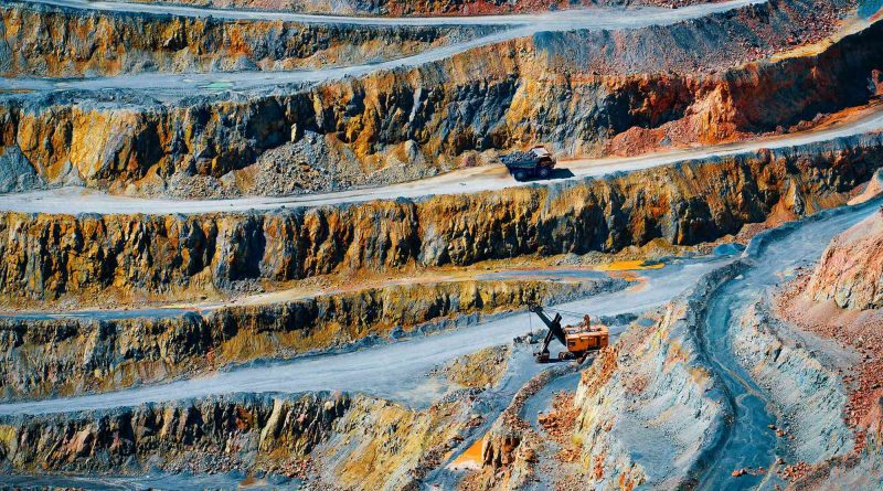 An open-pit critical minerals mine with heavy equipment operating beneath layered rock formations, representing China's expanding overseas mining investment strategy.